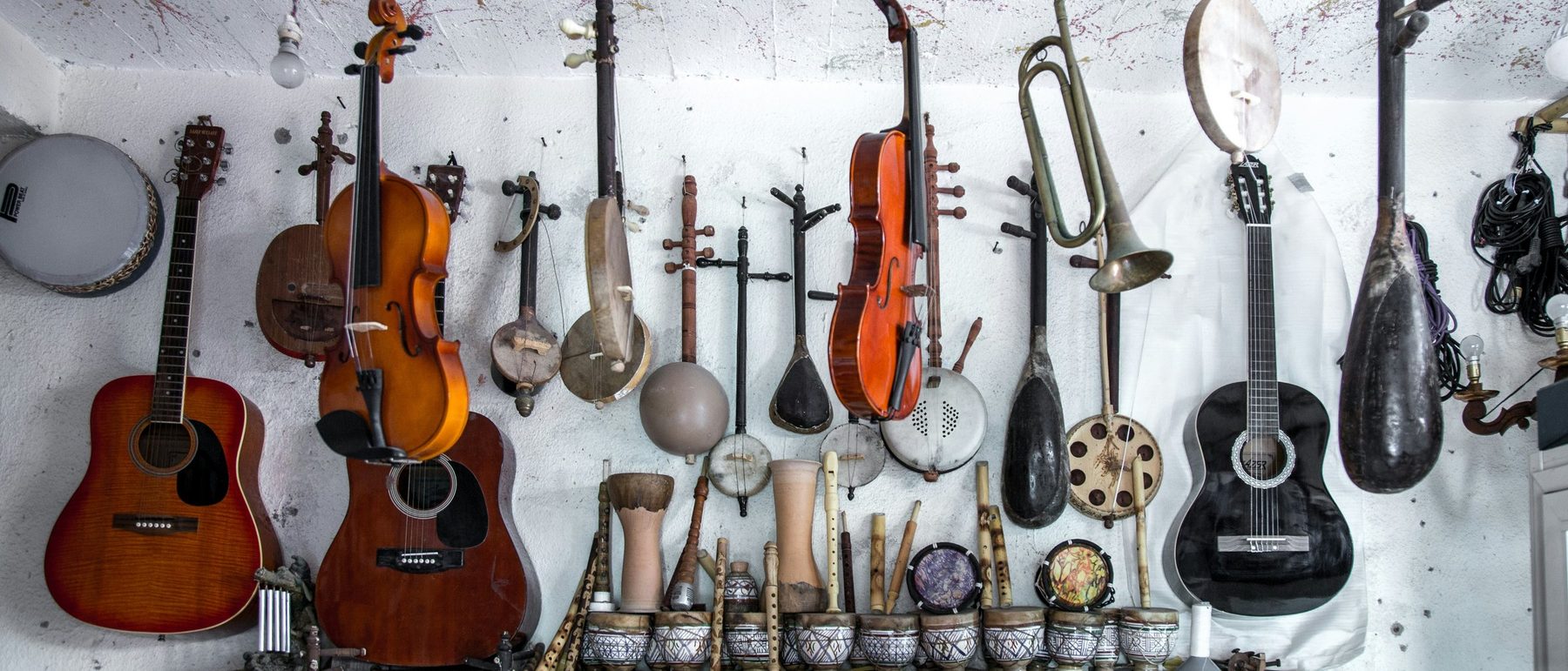 Guitars, bowed instruments and brass hung on a workshop wall